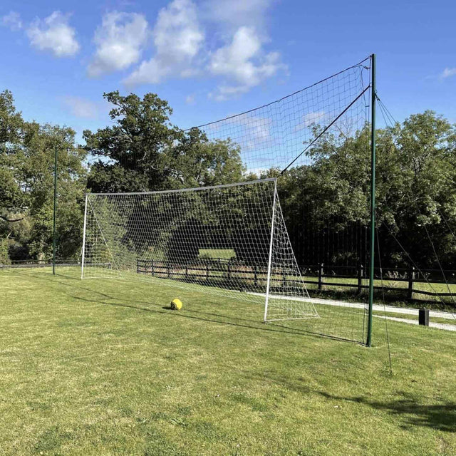 Rear view of Open Goaaal Regulation football goal showing backstop netting and rebounder system on a grass pitch