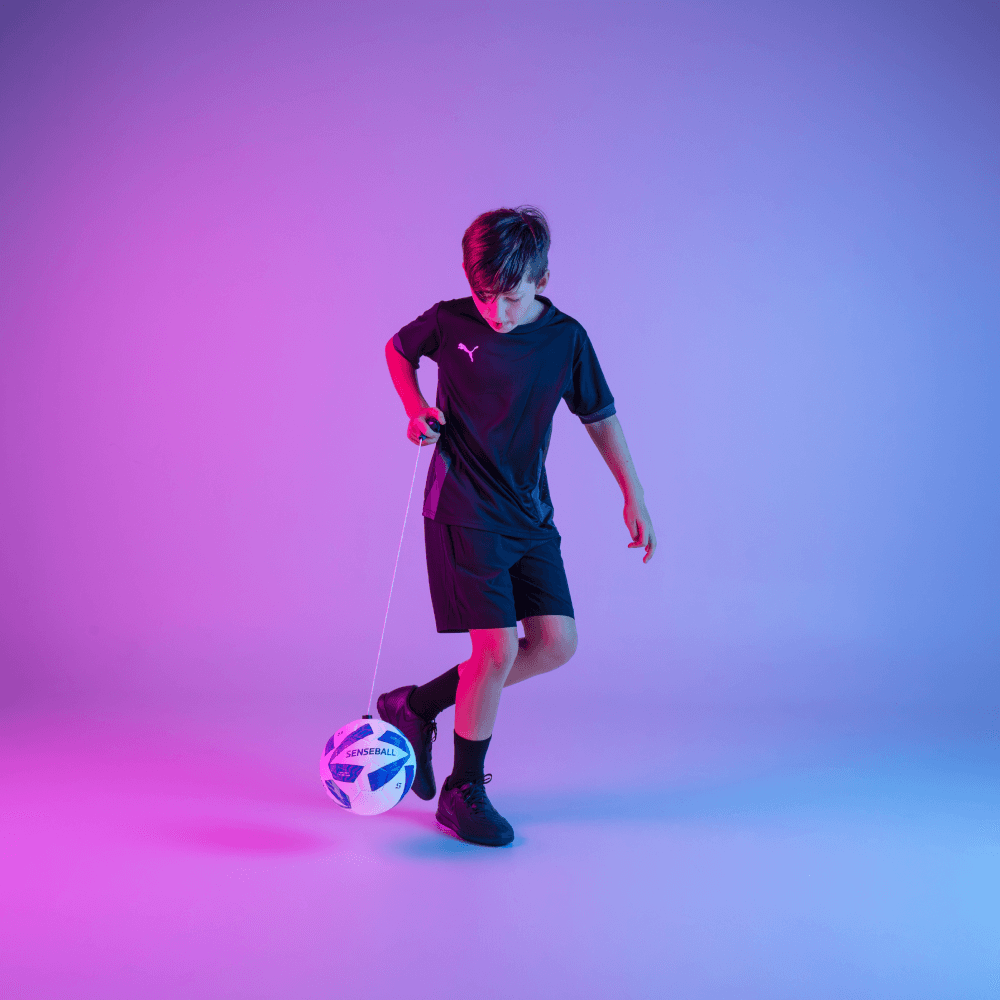 Football Kick Trainer being used by a young player, featuring a blue size 3 SenseBall designed for improving soccer skills and coordination.